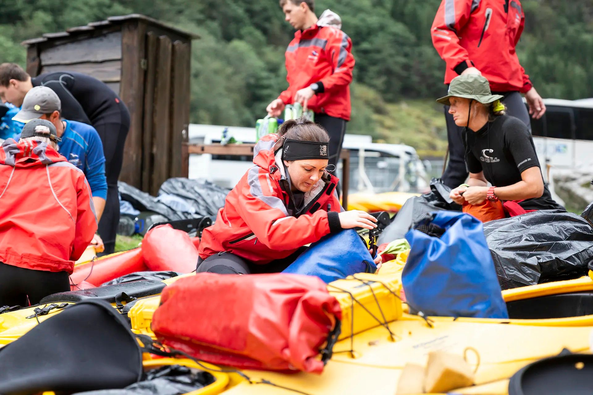 Un gruppo di turisti prepara il proprio kayak; in primo piano, una donna prepara una sacca per il secco